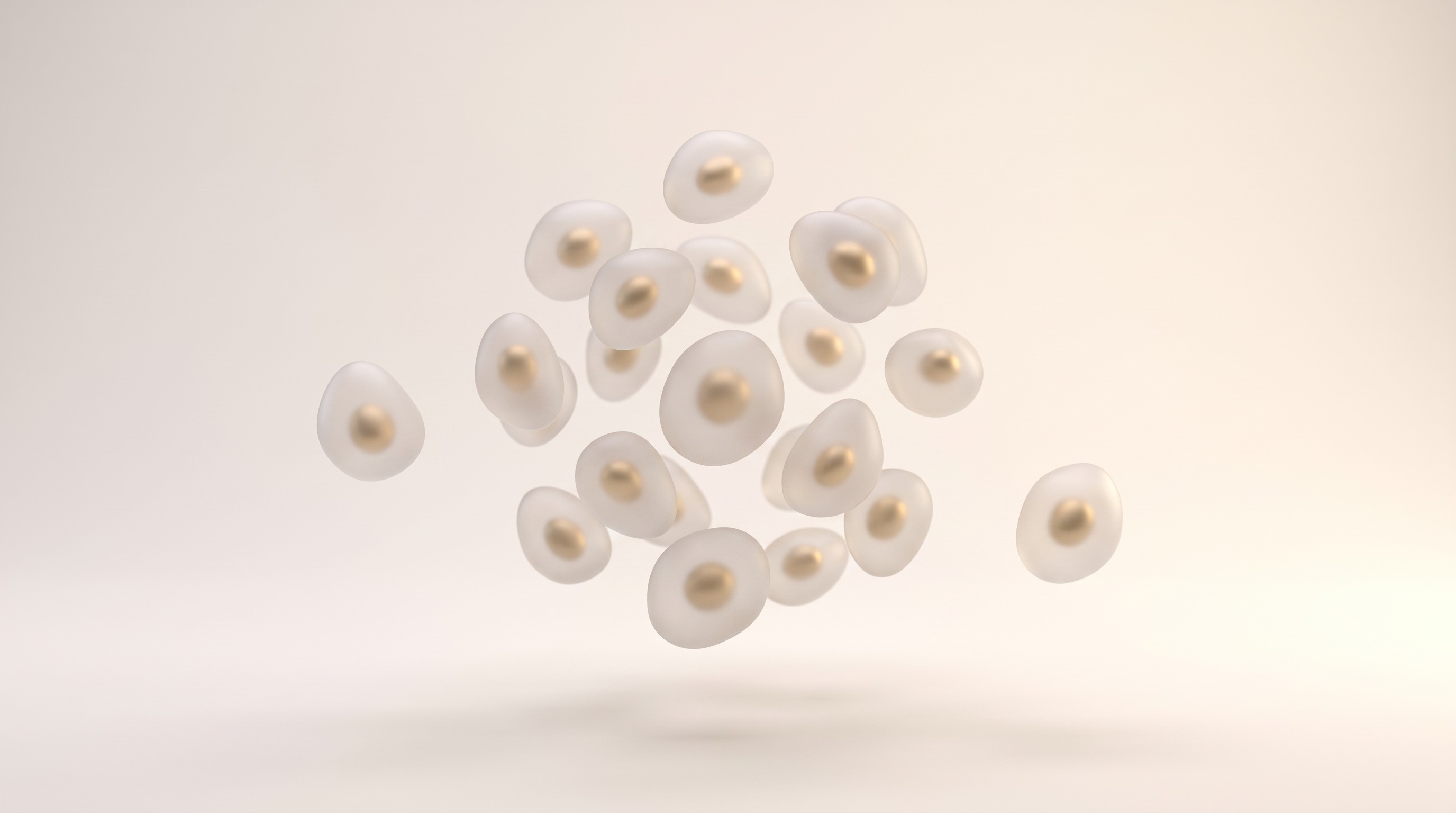Rendered cluster of rounded translucent cells, each with a gold nucleus visible inside, two drifting away from the group