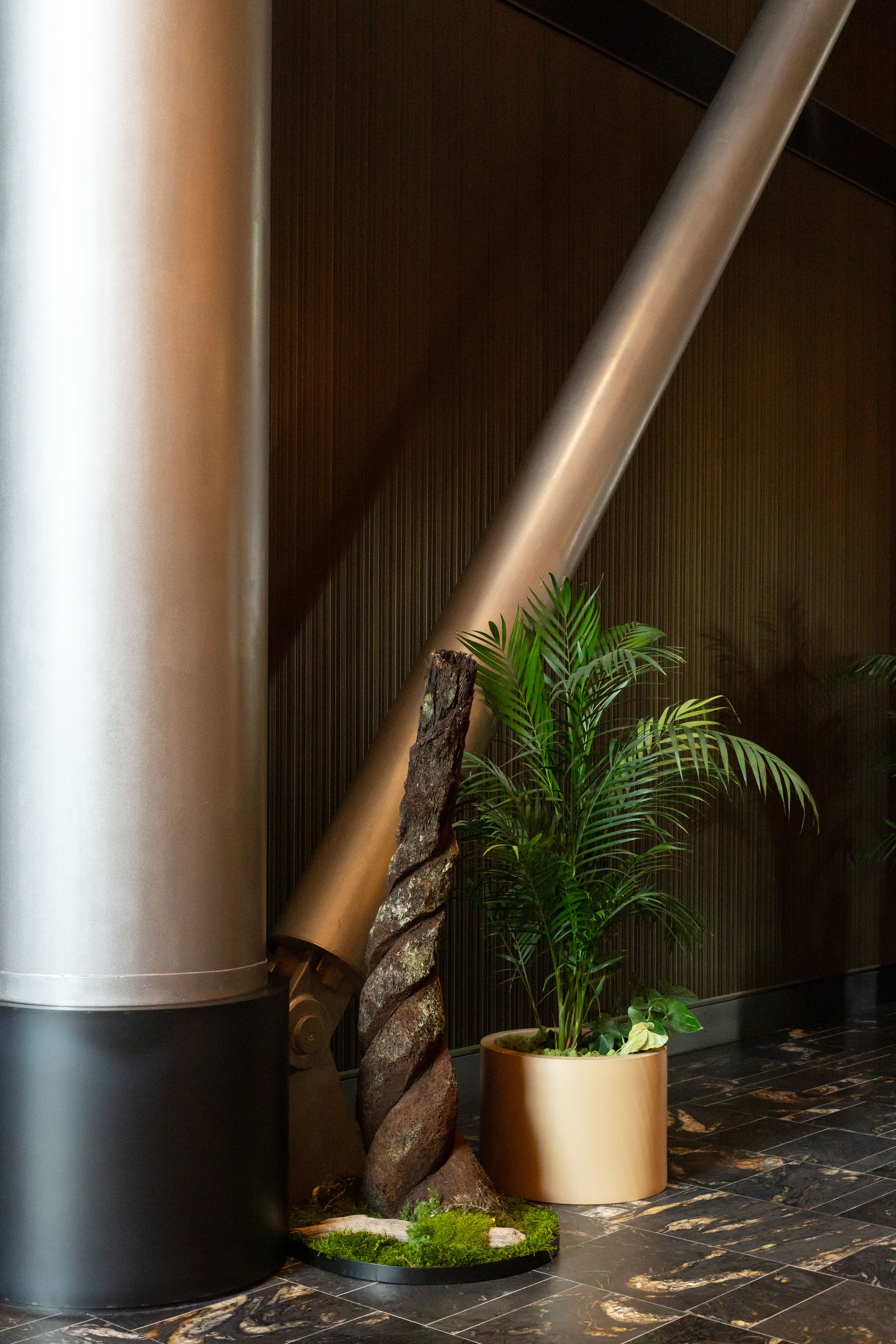 Carved punga log and moss garden beside a structural column at NZICC Auckland by GreenAir, bringing native forest texture into the arrival space