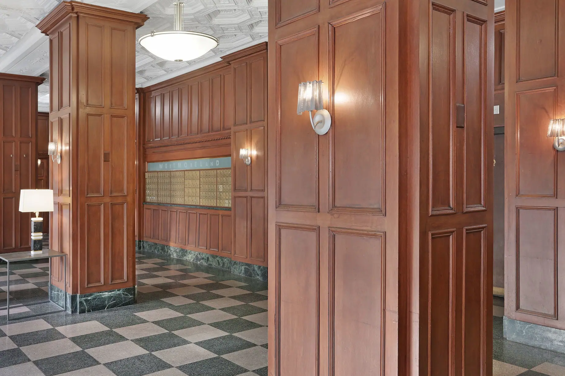 Lobby with wooden panel walls, green and beige checkered floor, mailbox wall labeled Westmoreland.