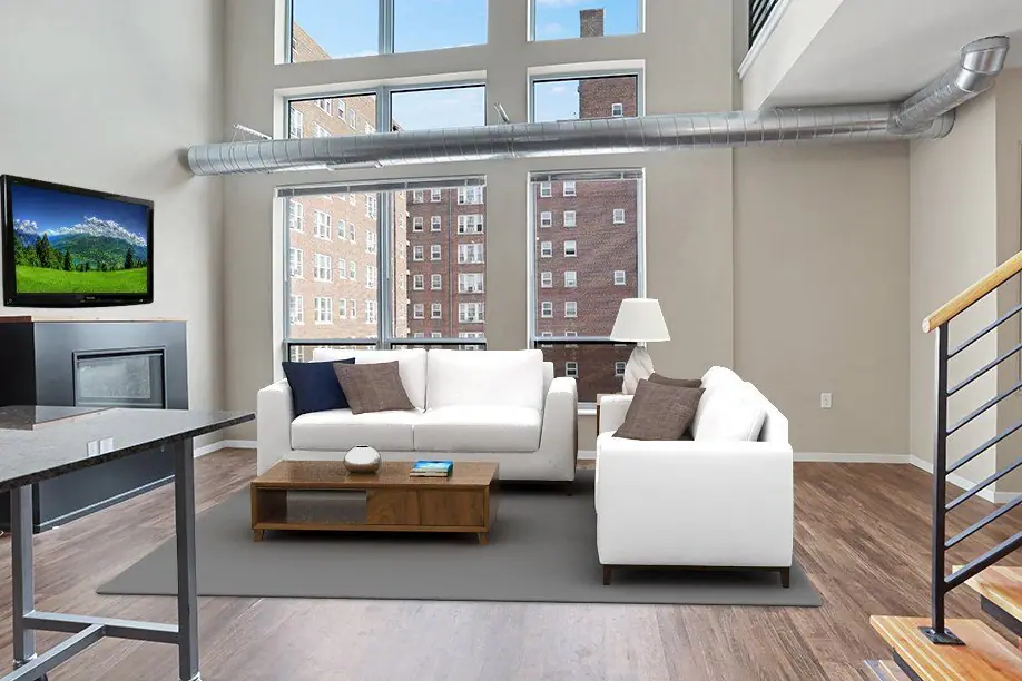 Bright modern living room with white sofas, wood coffee table, large windows, and exposed ductwork.