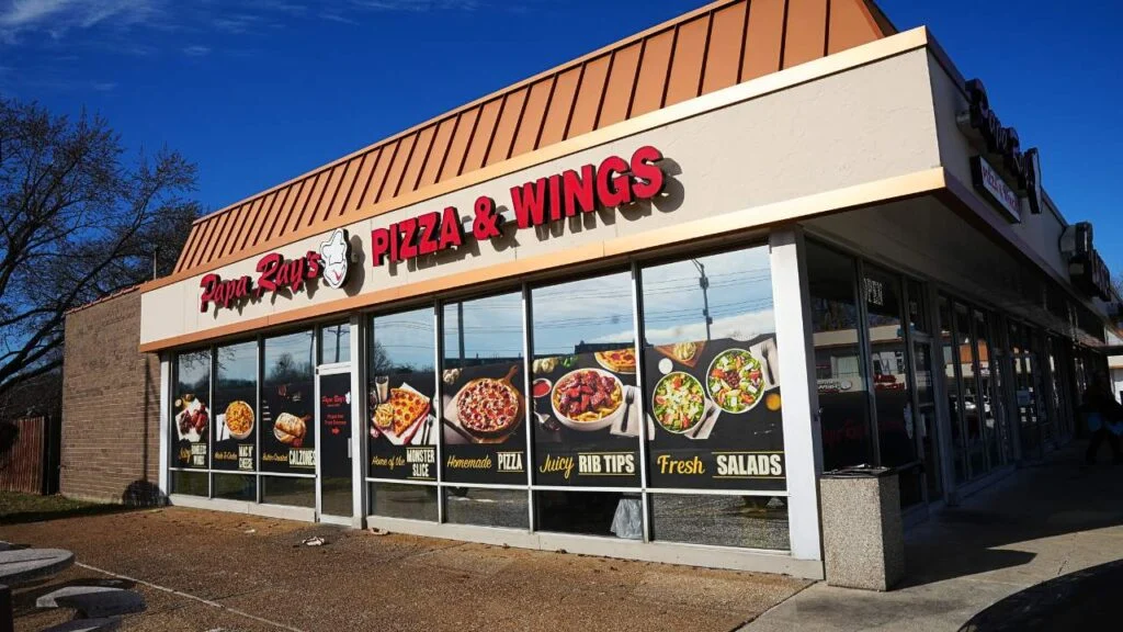 Papa Rays Pizza & Wings restaurant with window ads showing pizza, rib tips, calzones, and salads.