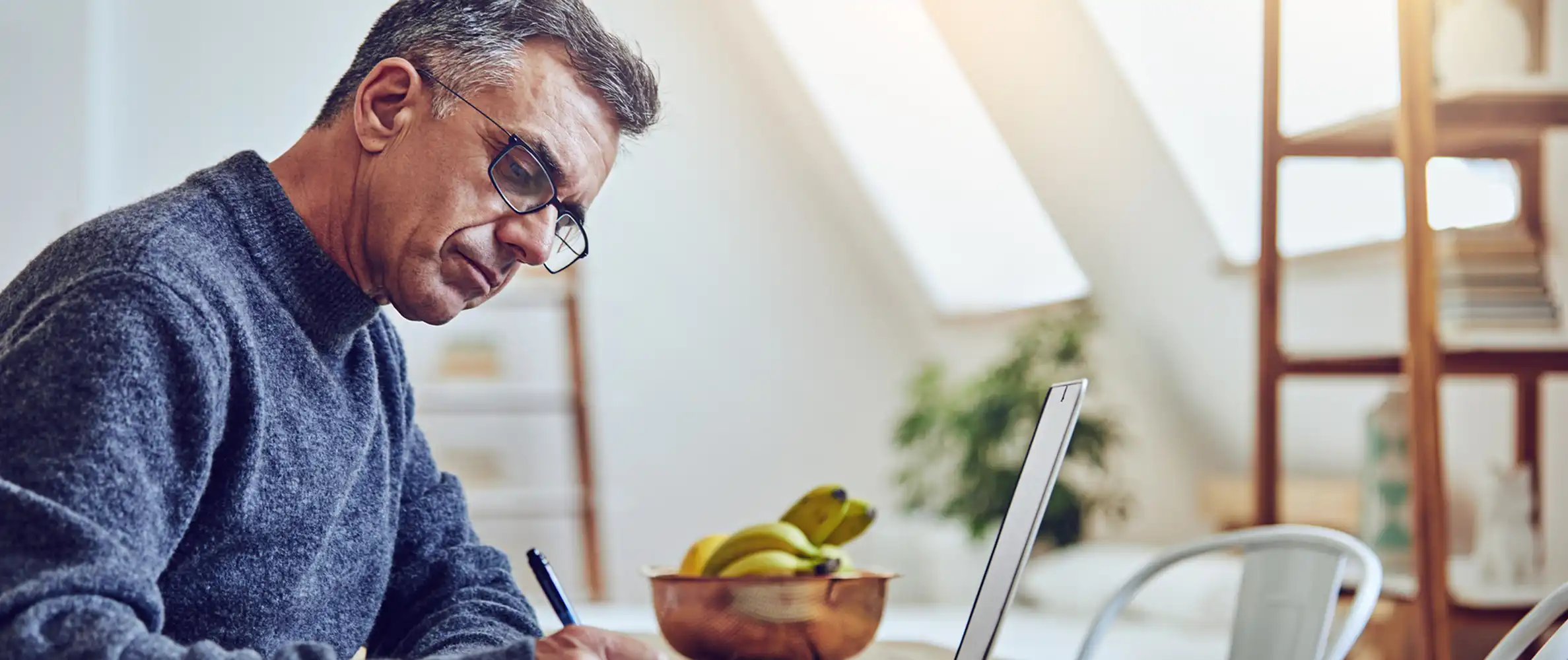 A male creator working and writing at a home office.