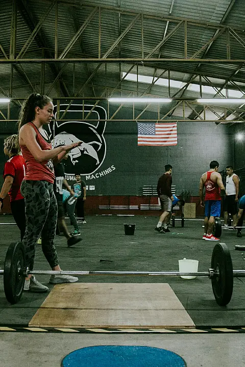 CrossFit gym interior featuring workout equipment and athletes engaged in training activities.