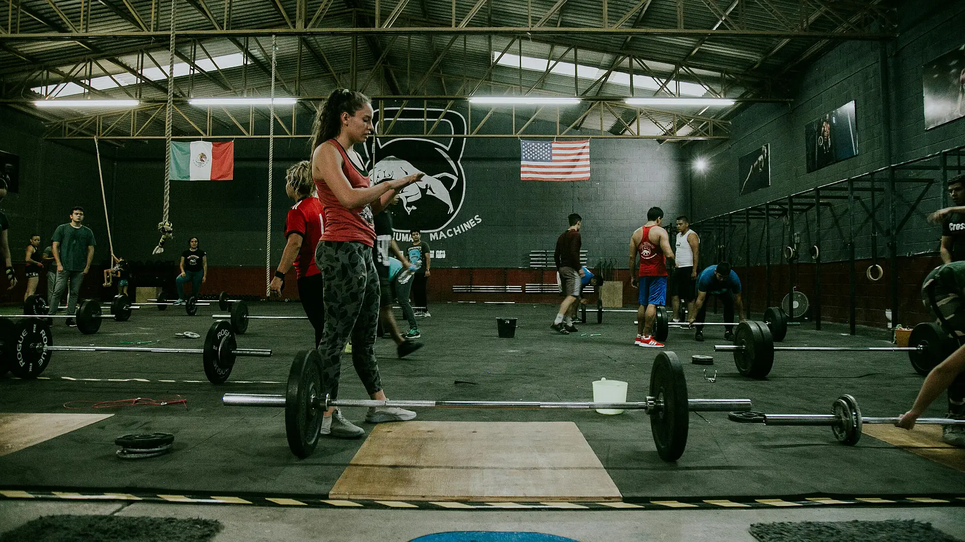 CrossFit gym interior featuring workout equipment and athletes engaged in training activities.