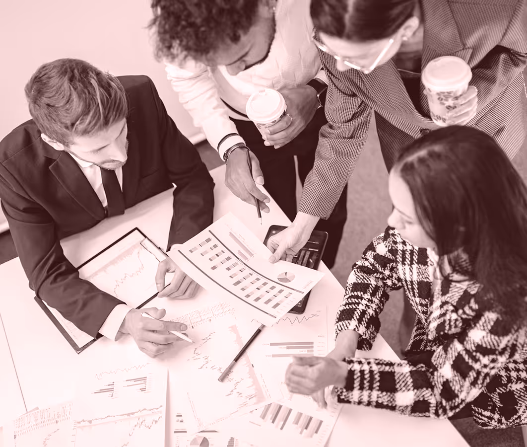 Four professionals gathered around a table reviewing financial charts and graphs.