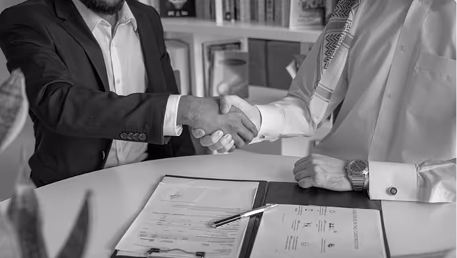 Success with CAPDA. Two businessmen shaking hands over a desk with documents and a pen.