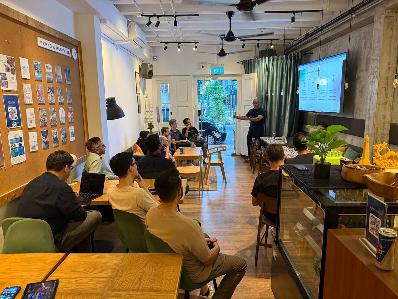 Audience in a cafe watching a presenter at a MISSION+ demo, debate and drinks event on the Airia AI platform
