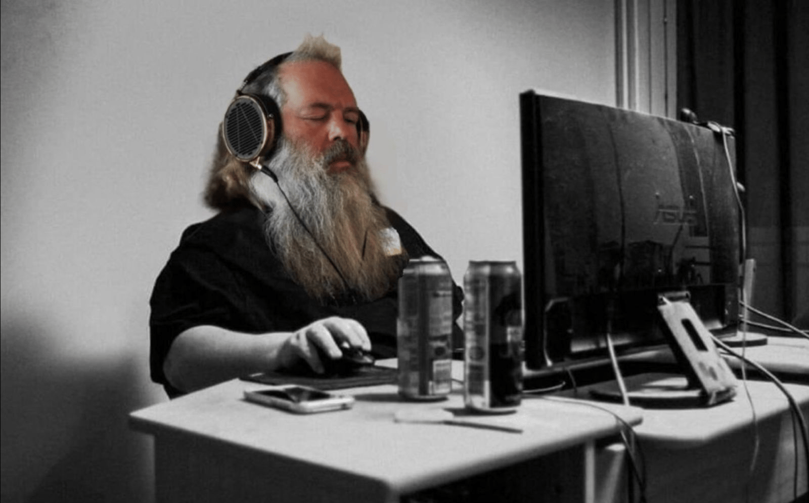 Bearded man in headphones with eyes closed at a computer, beer cans on the desk, the vibe coding mood