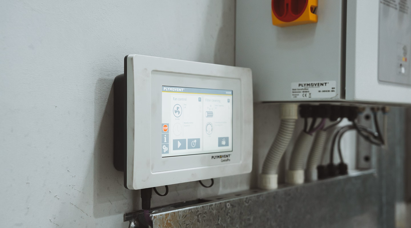 Plymovent system control touchscreen with emergency stop button on a plant room wall