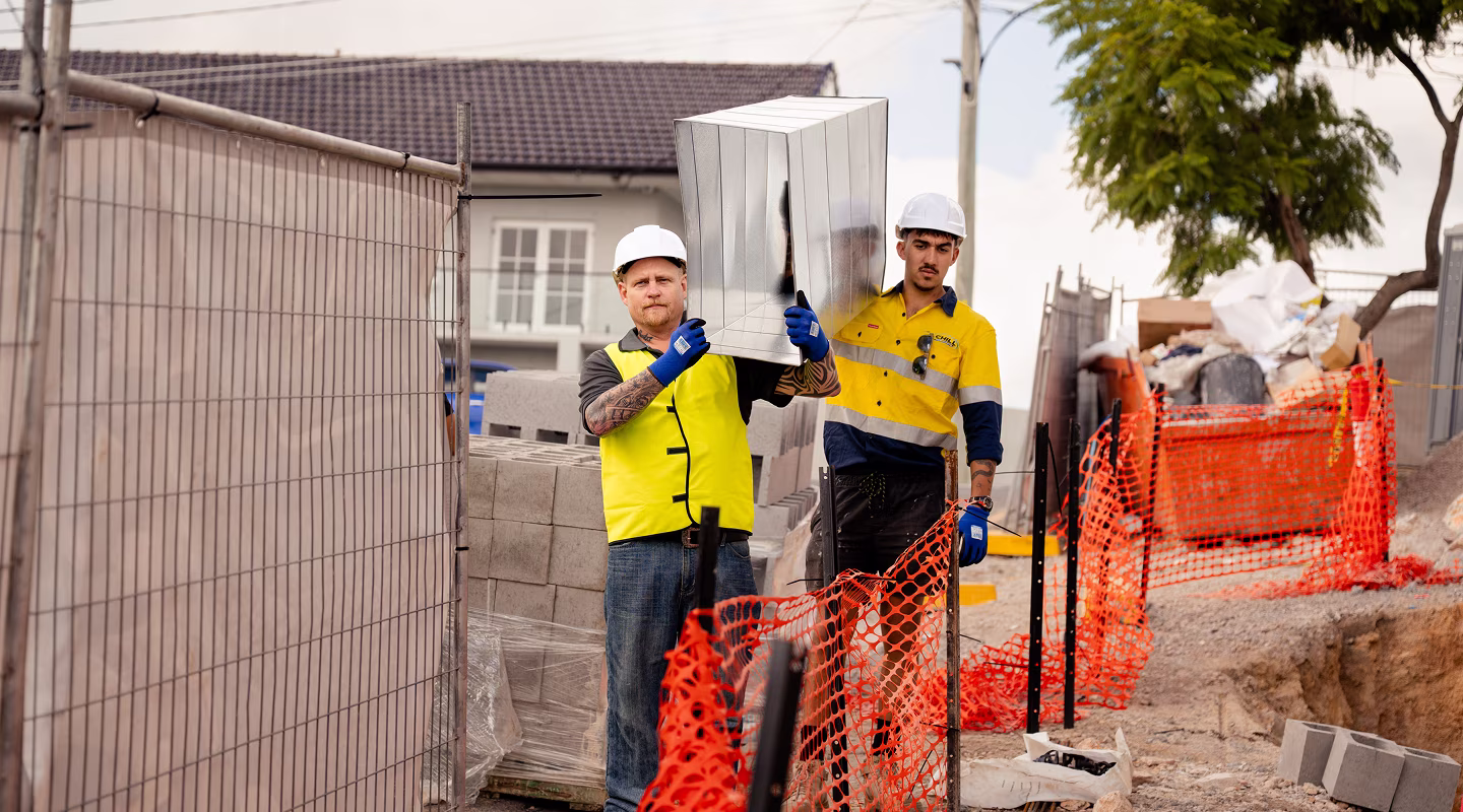 Two Chill Merchants technicians in hi-vis on a construction site with condenser units
