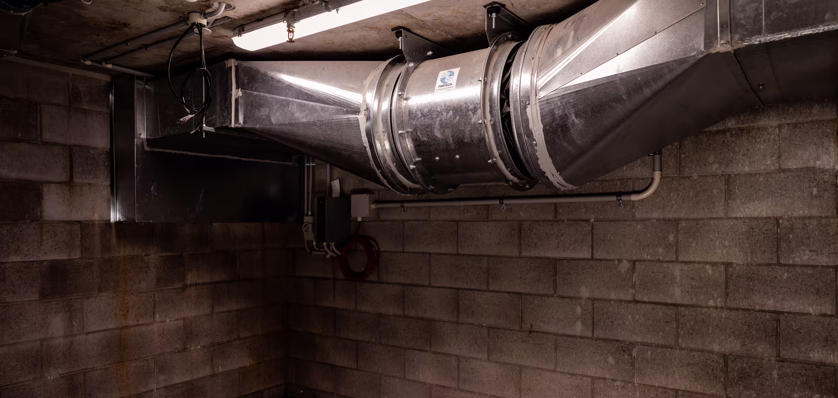 Large galvanised steel mechanical exhaust ductwork and connections installed in a commercial building plant room