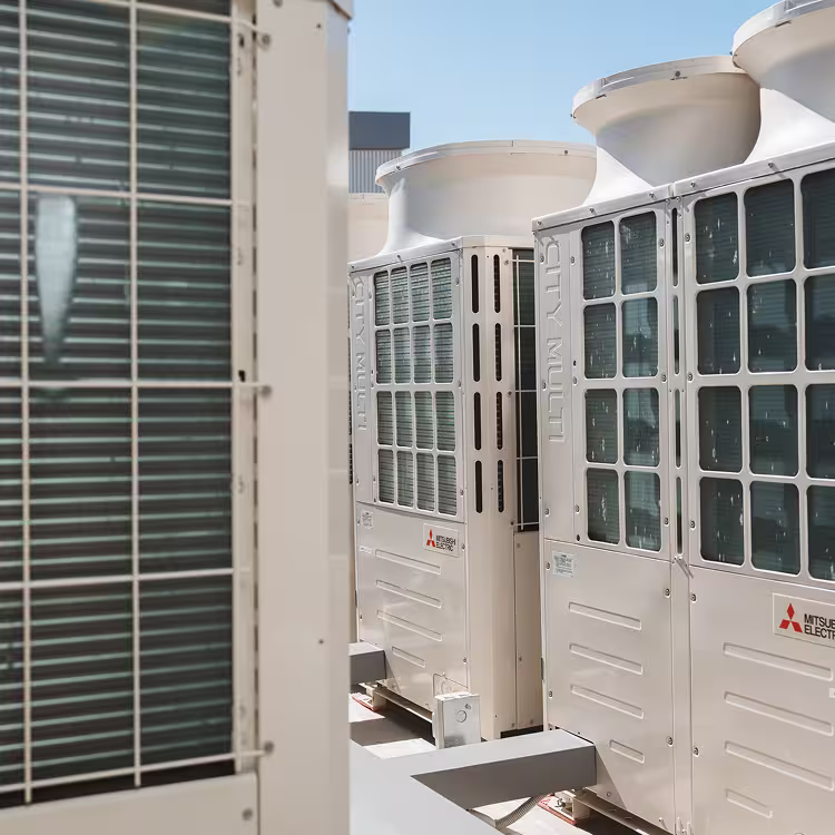 Close-up view of two Mitsubishi Electric City Multi outdoor air conditioning units mounted against a building wall.