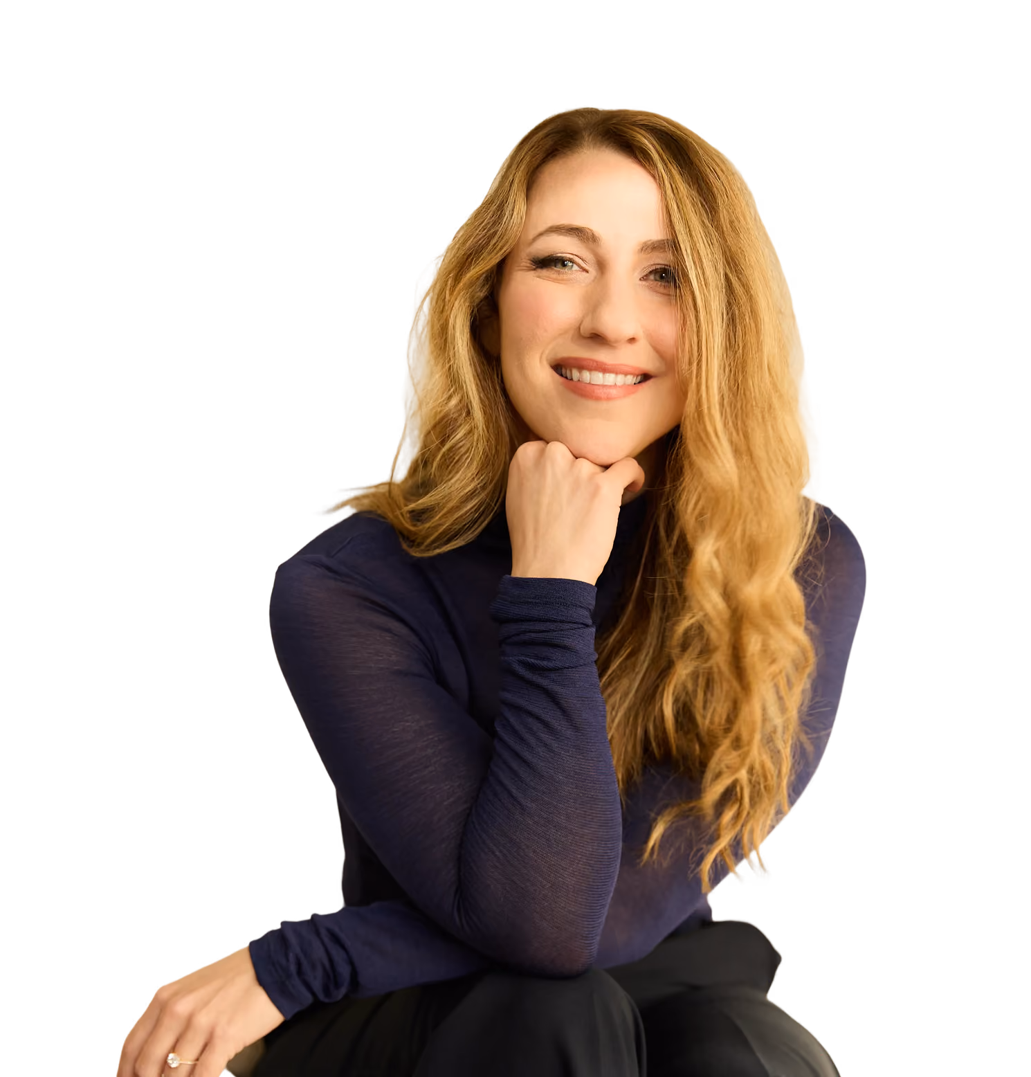 Smiling woman with long curly blonde hair wearing a navy blue turtleneck, resting chin on fist.