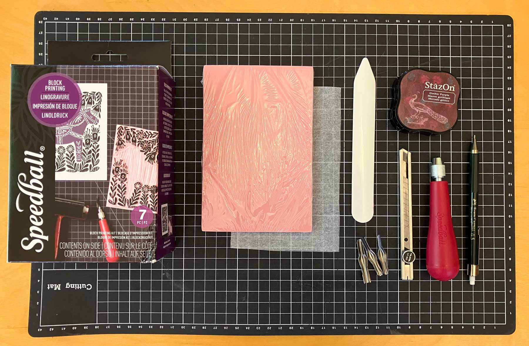 Everything laid out before getting started – the Speedball Speedy Carve block, baking paper, bone folder, StazOn ink, pad lino cutters, Craft knife, and pencil laid out on a cutting mat