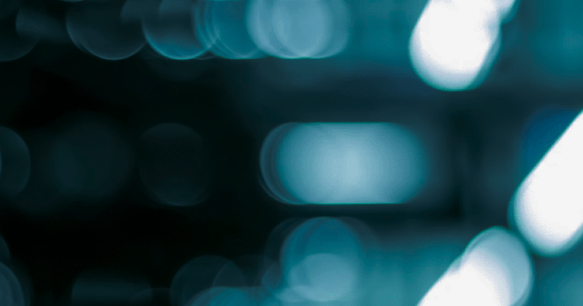 Abstract close-up texture with soft blue and teal circular light forms against a dark background.