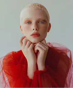 Portrait of a model wearing a red sheer dress with hands near face