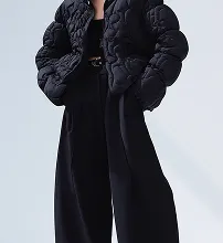 Model wearing an oversized black quilted jacket and wide-leg trousers