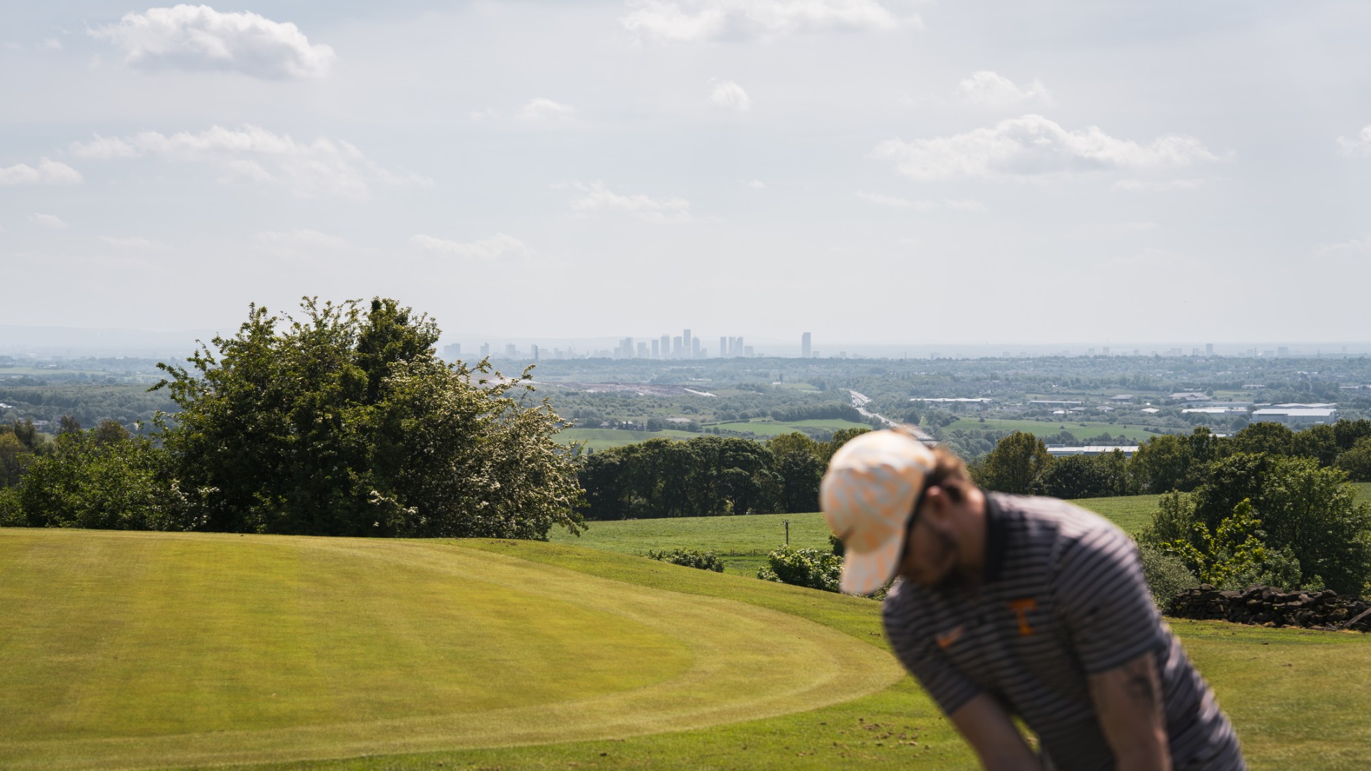 Golfer on the course at WGC Bury with far-reaching views across the countryside to the city skyline