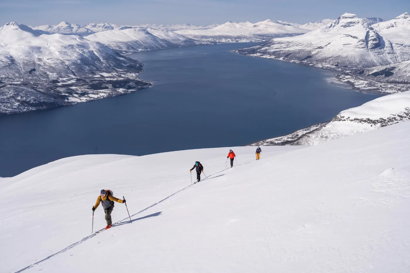 Skupina skialpinistů stoupá nad Lyngenfjordem