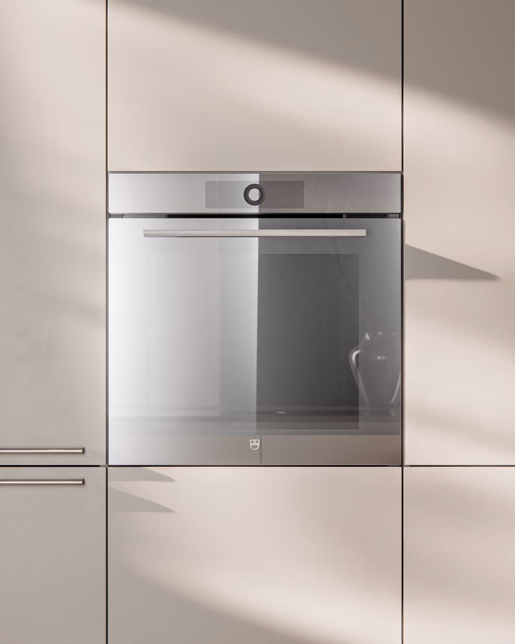 Eingebauter moderner Backofen in cremeweißer Kücheneinrichtung mit Edelstahlgriff.