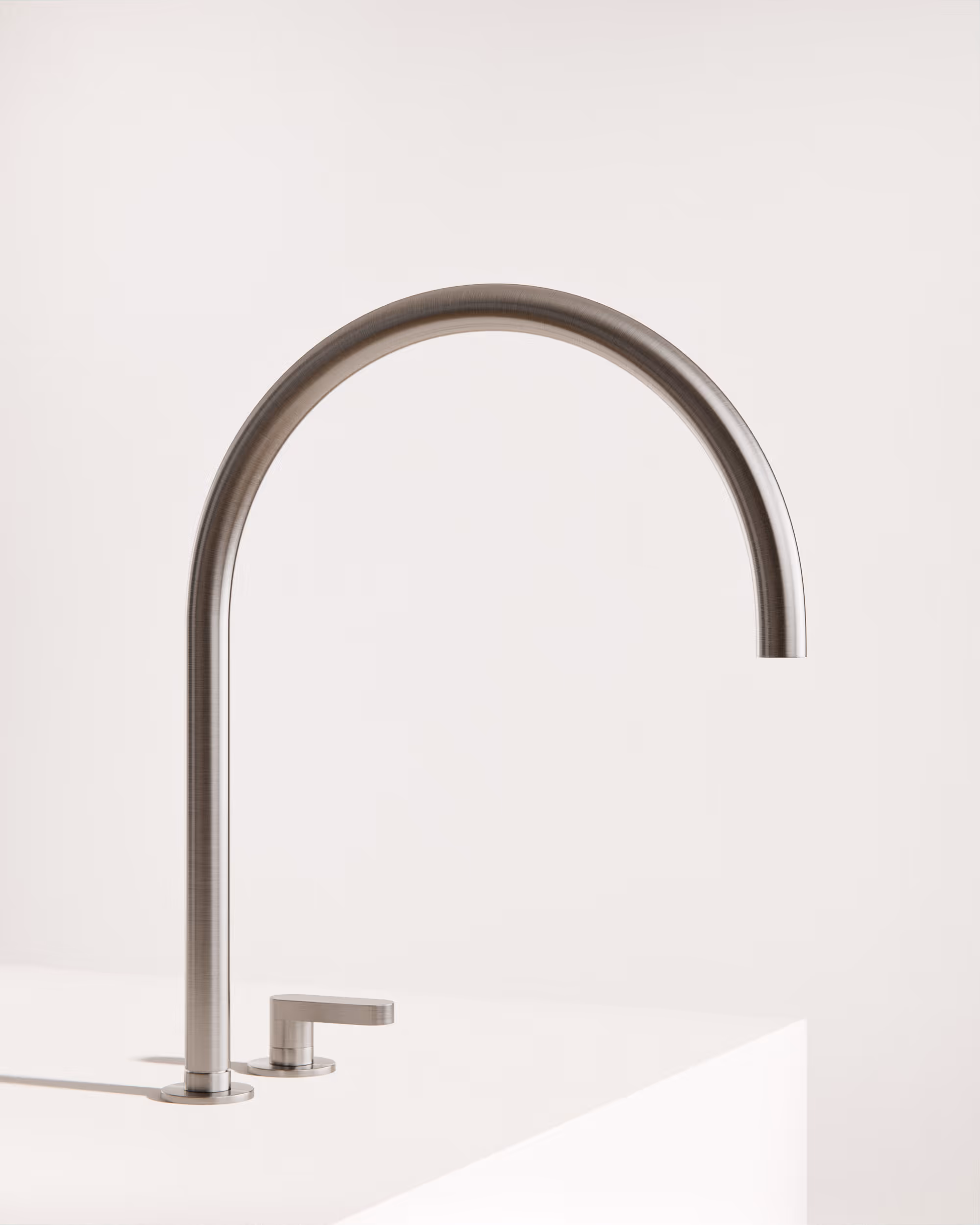 Moderner gebürsteter Edelstahl-Küchenwasserhahn mit hohem Bogen auf weißer Arbeitsplatte.
