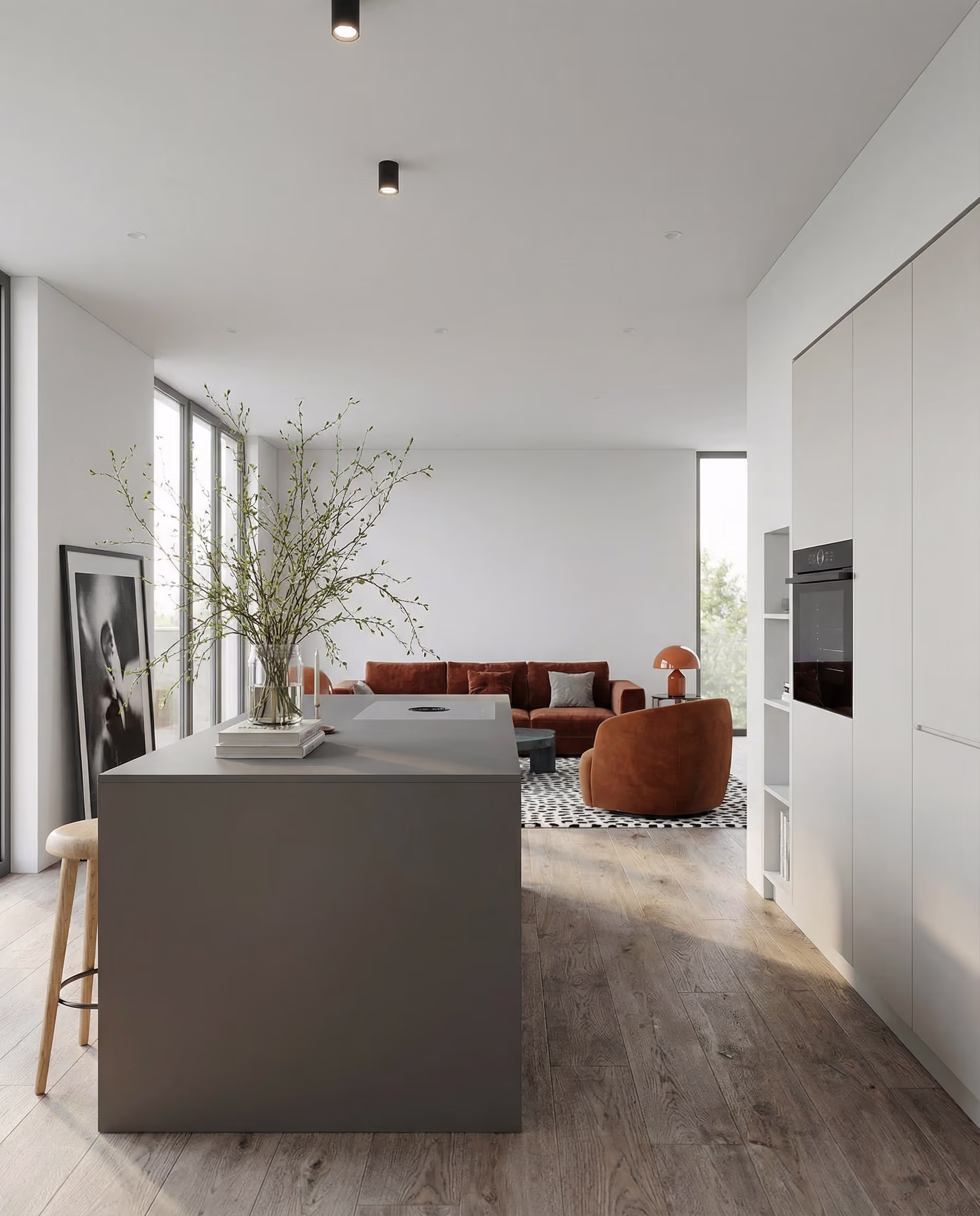 Offene minimalistische Küche mit grauer Insel, samtbraunen Stühlen und einem Sofa.