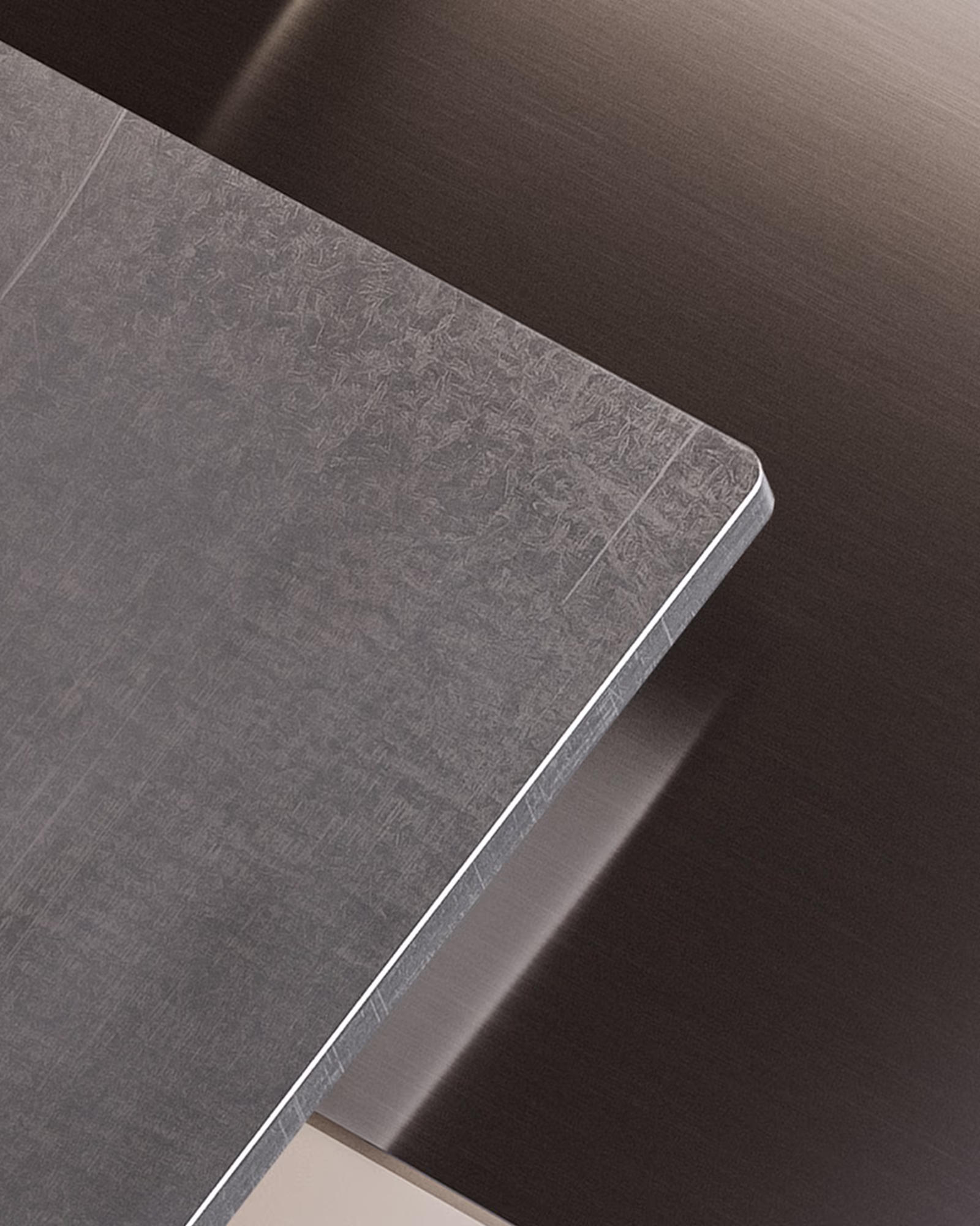 Ecke einer matten, gebürsteten Stahlplatte vor dunklem, glänzendem Metallhintergrund.