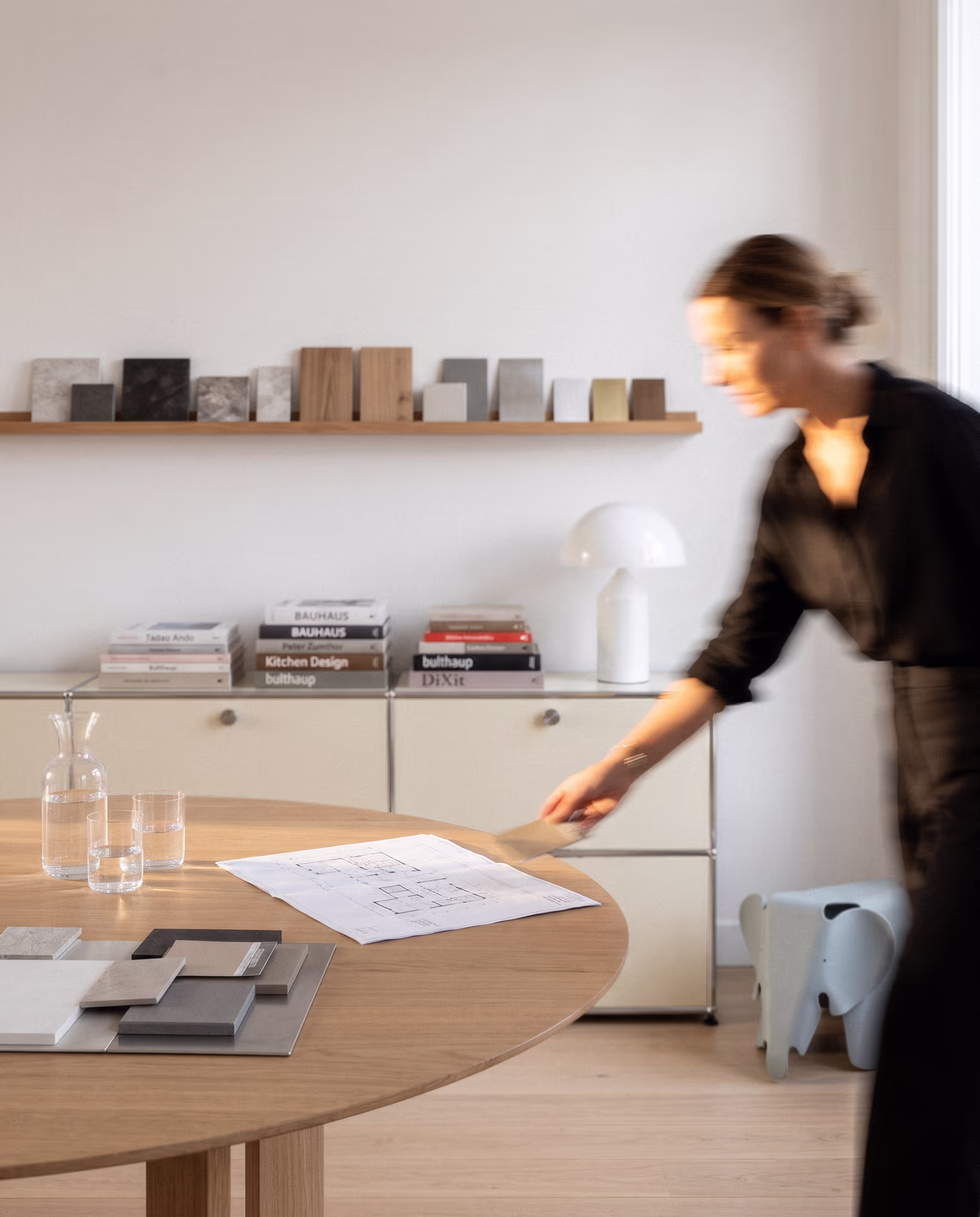 Drei Männer unterhalten sich locker in einer modernen, minimalistischen Küche mit weißen Schränken und Holzfußboden.