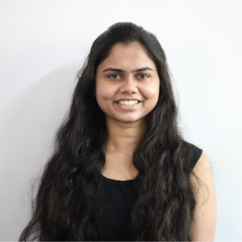 Smiling woman with long dark hair wearing a sleeveless black top against a white background.