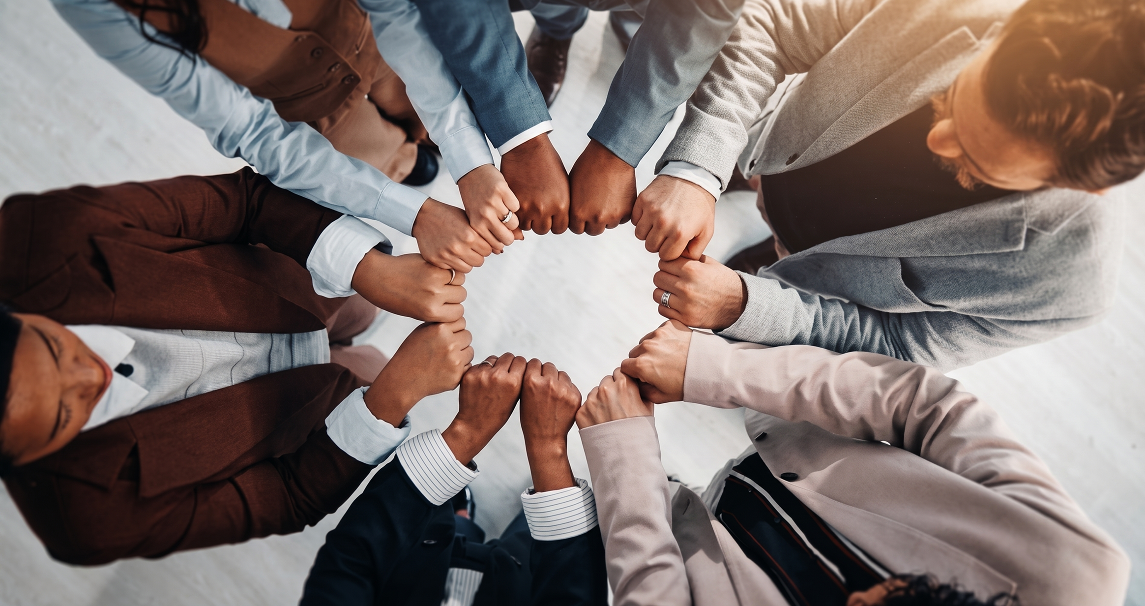 Top view of diverse business people standing in a circle with fists joined together showing teamwork.