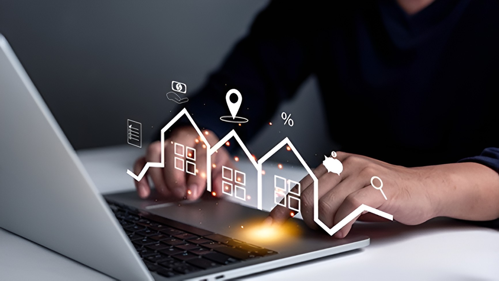 Person typing on a laptop with floating digital icons of houses, location, percentage, and piggy bank representing real estate and finance.