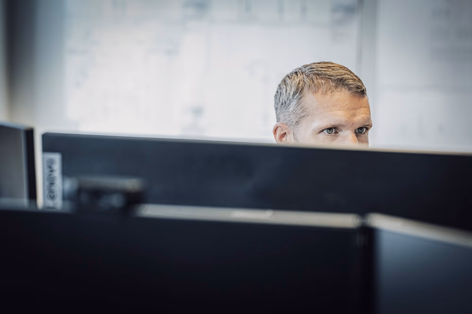 Terotech employee focused on work behind computer monitors in an office setting.