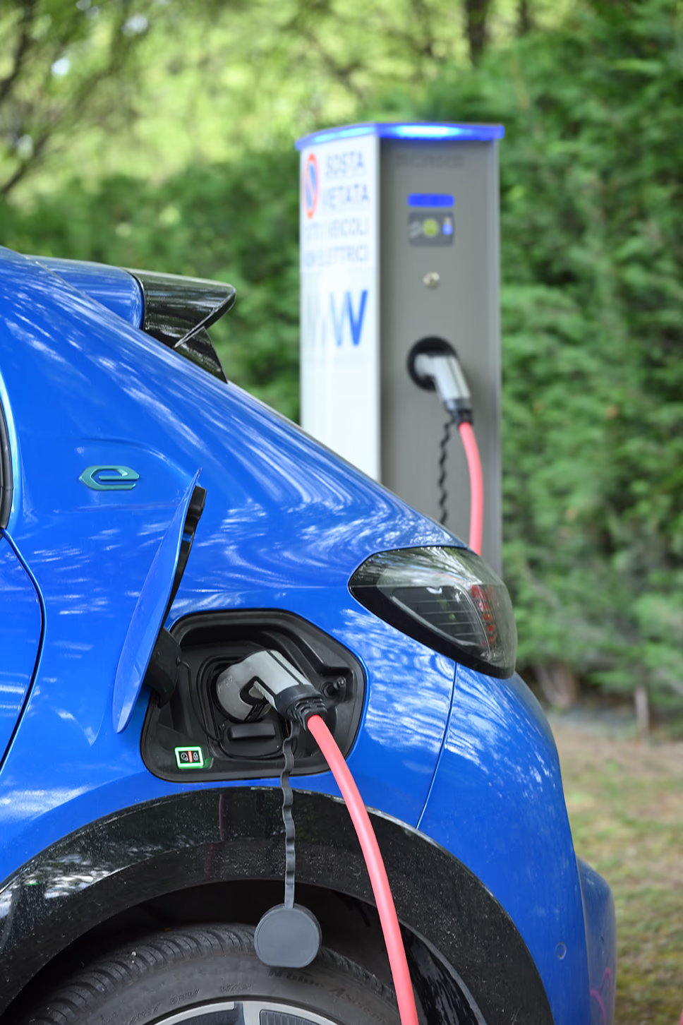 Auto elettrica blu collegata a una colonnina di ricarica presso la sede aziendale MAW.