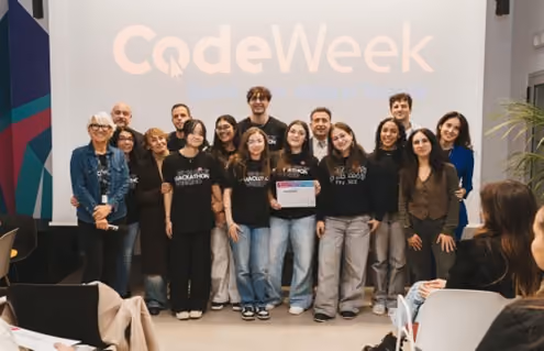 Gruppo di giovani partecipanti posano davanti a uno schermo con la scritta CodeWeek.