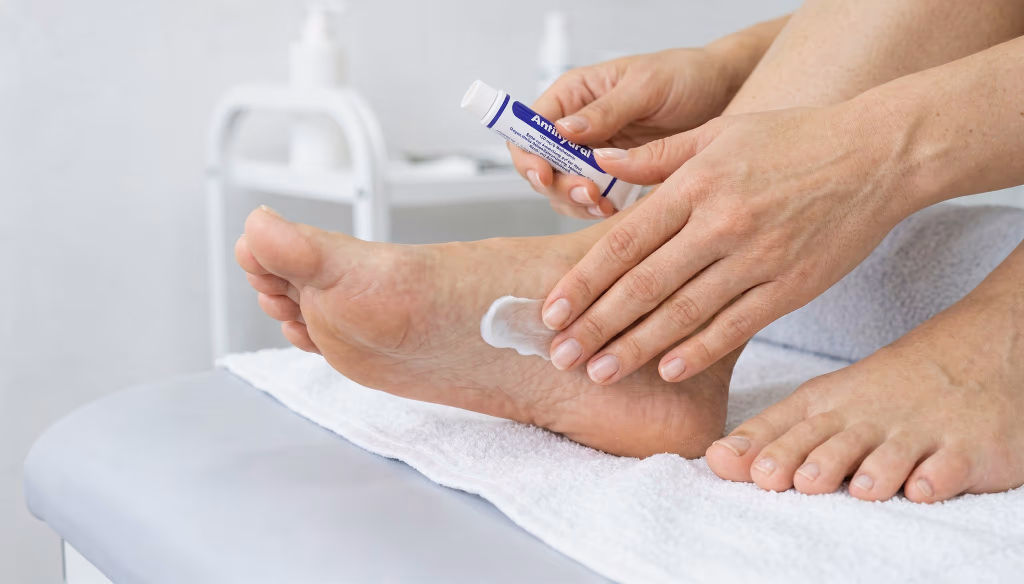 Person applying ointment onto feet.