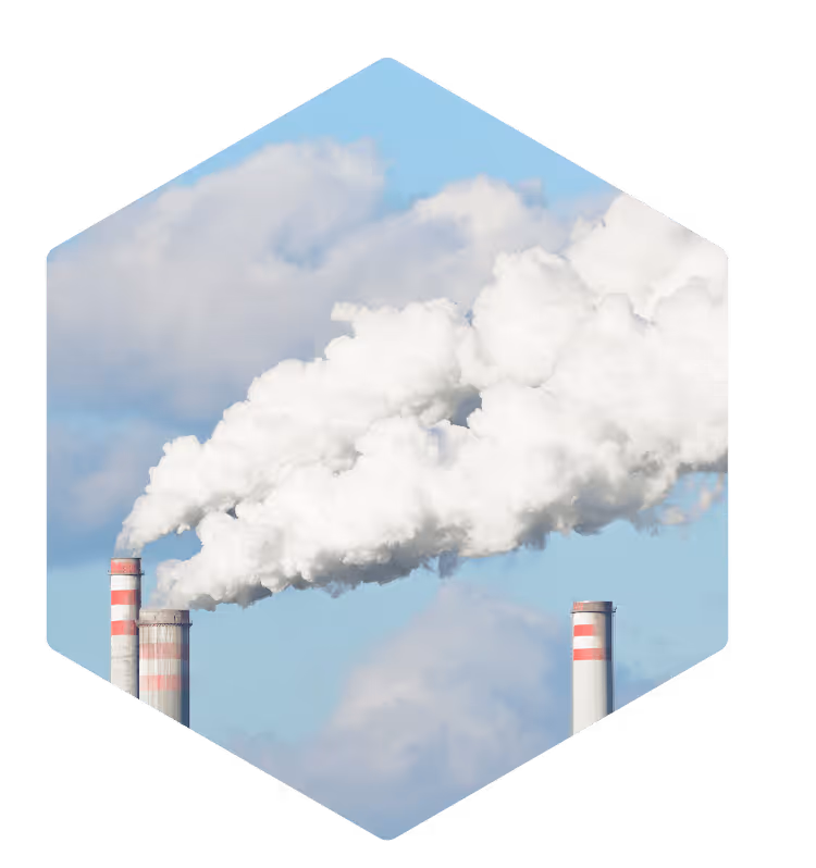 Industrial smokestacks emitting large white smoke clouds against a blue sky.