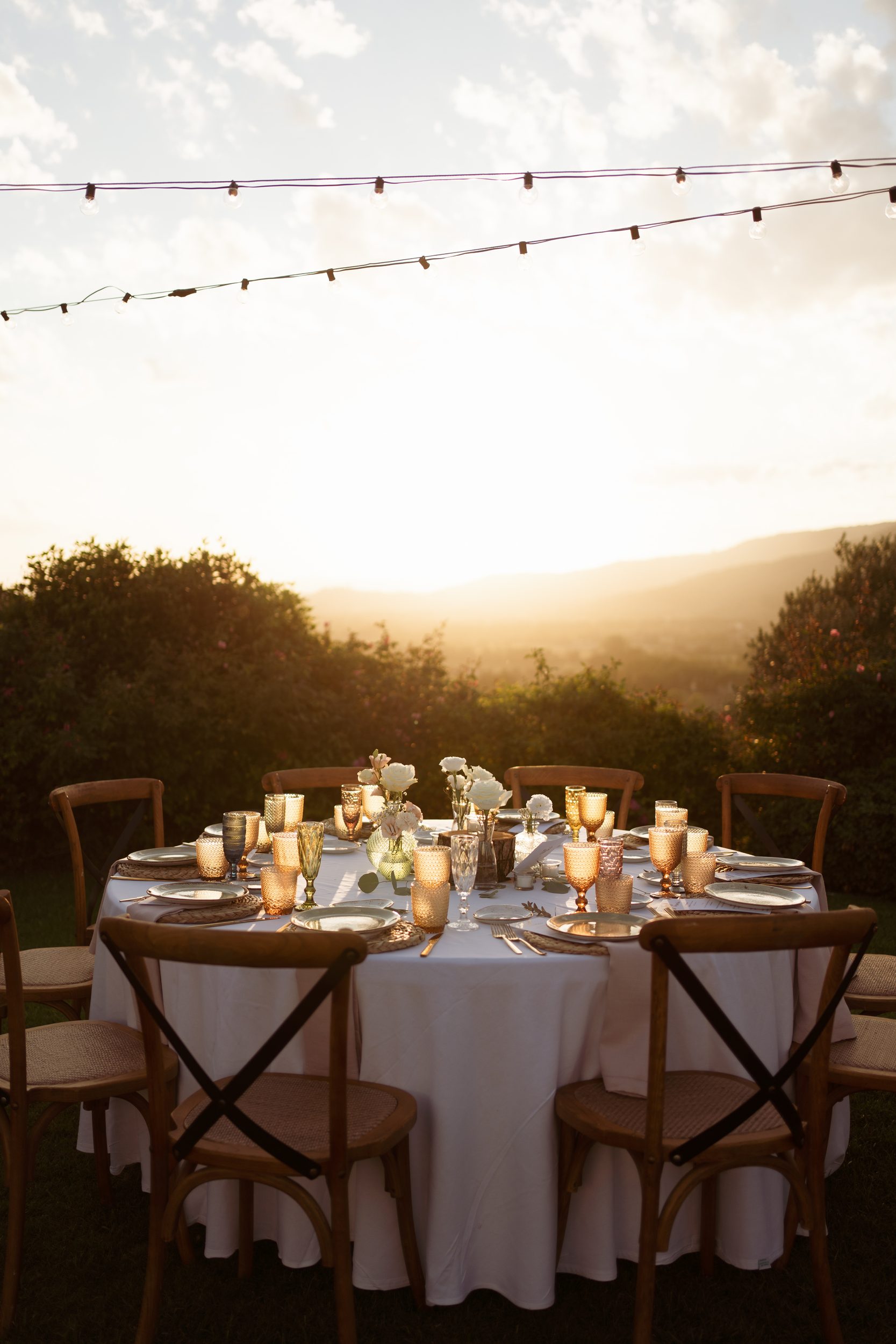 Golden-hour dinner table with candlelight and white florals at a Tuscany wellness retreat