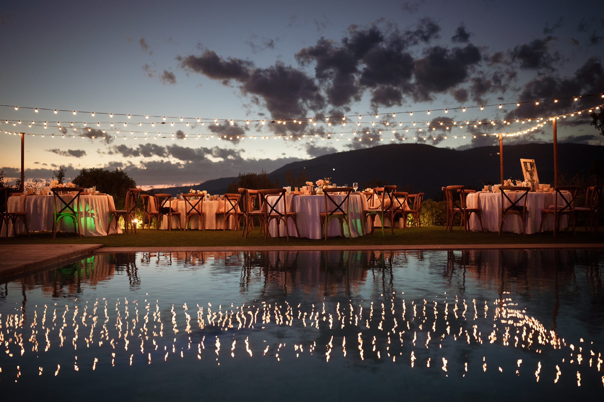 String lights reflected in the pool at dusk during the farewell dinner at a Tuscany retreat