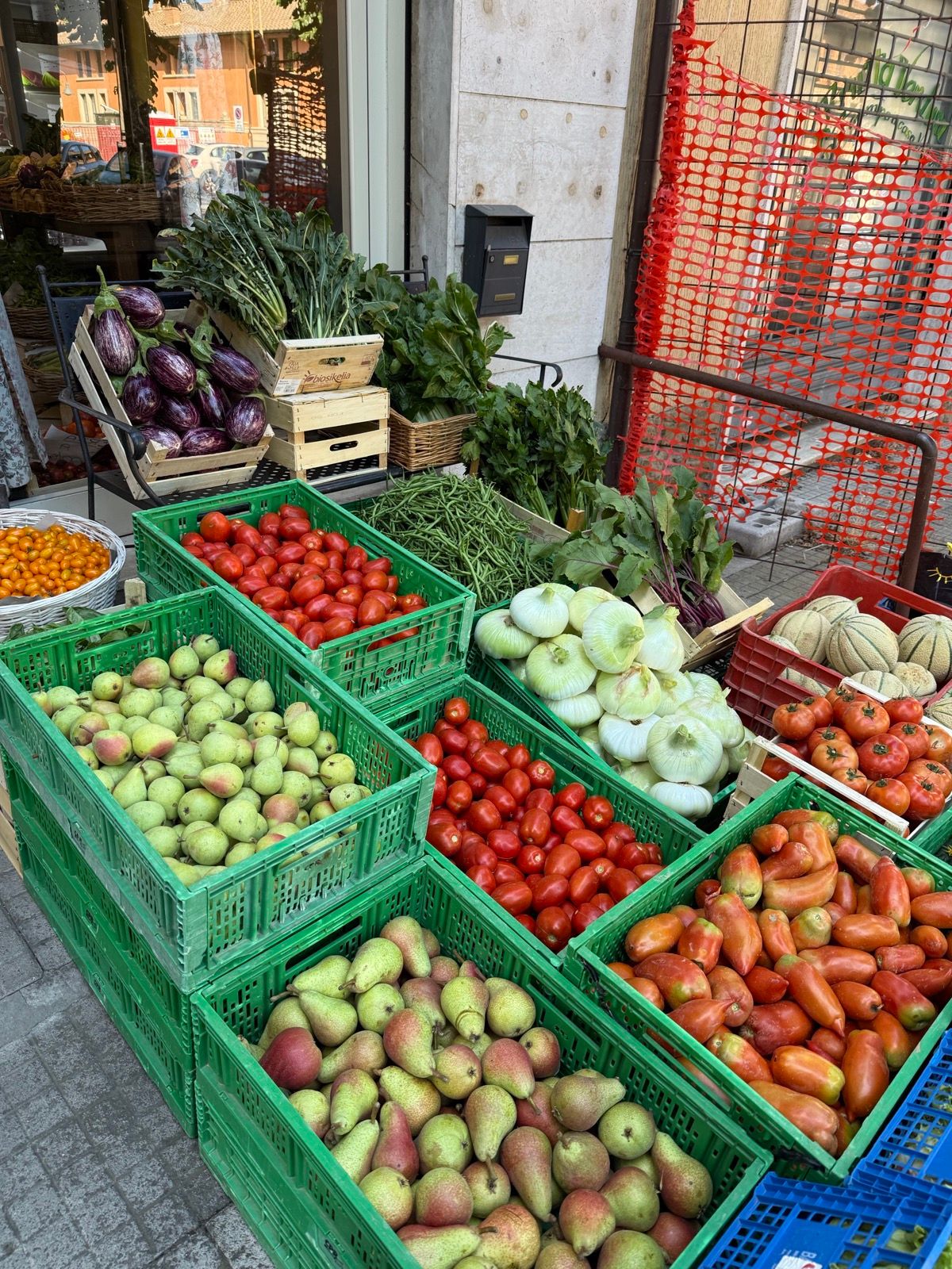 Crates of tomatoes, pears, onions, and eggplant at the Friday market stall in our town