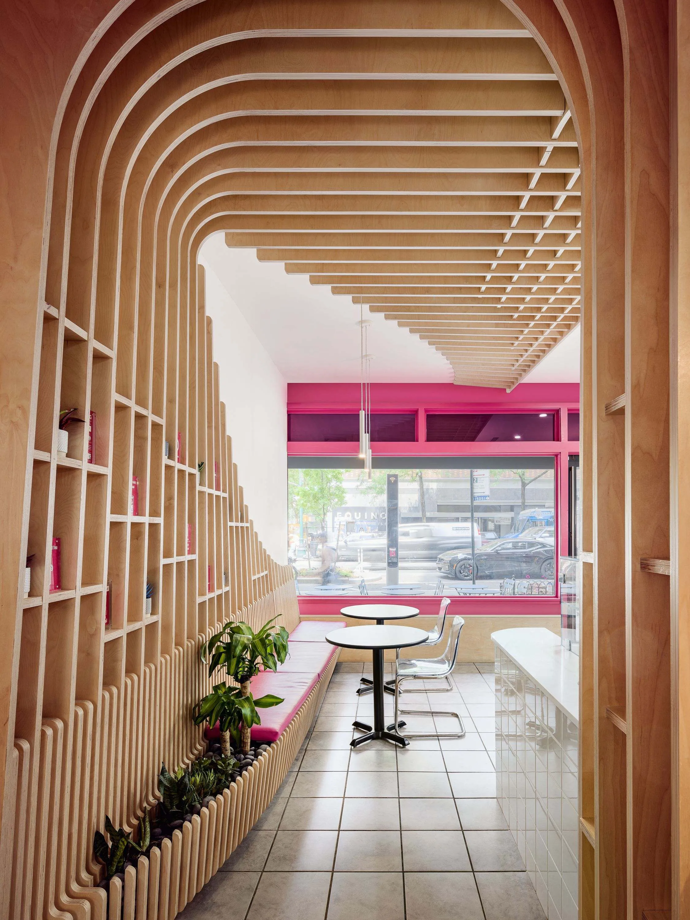 Narrow dining room framed by curved birch slats and shelving at The Migrant Kitchen, New York