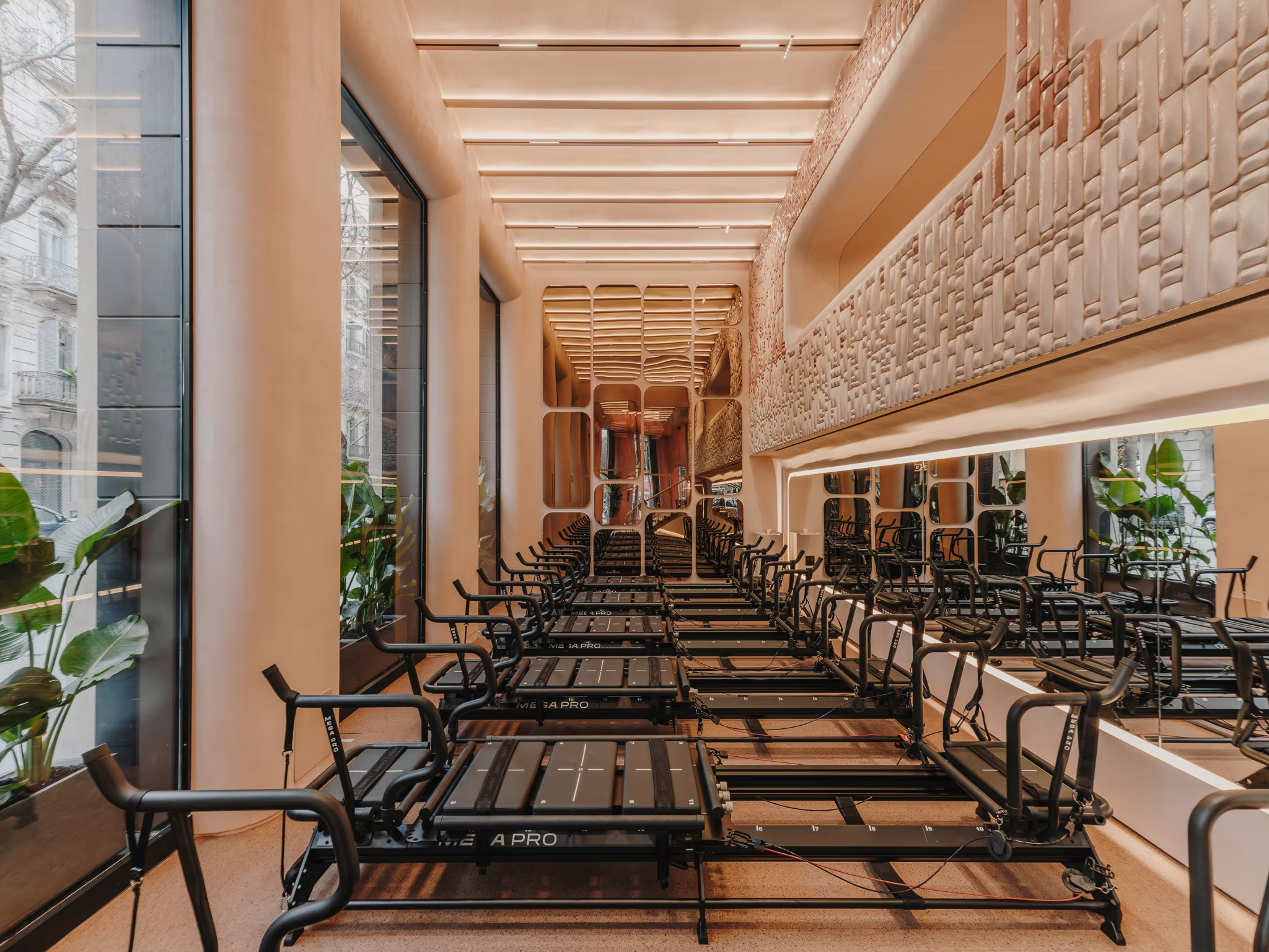 Reformer studio along the street windows of Repeat Wellness Club, Barcelona, beneath a textured ceramic wall