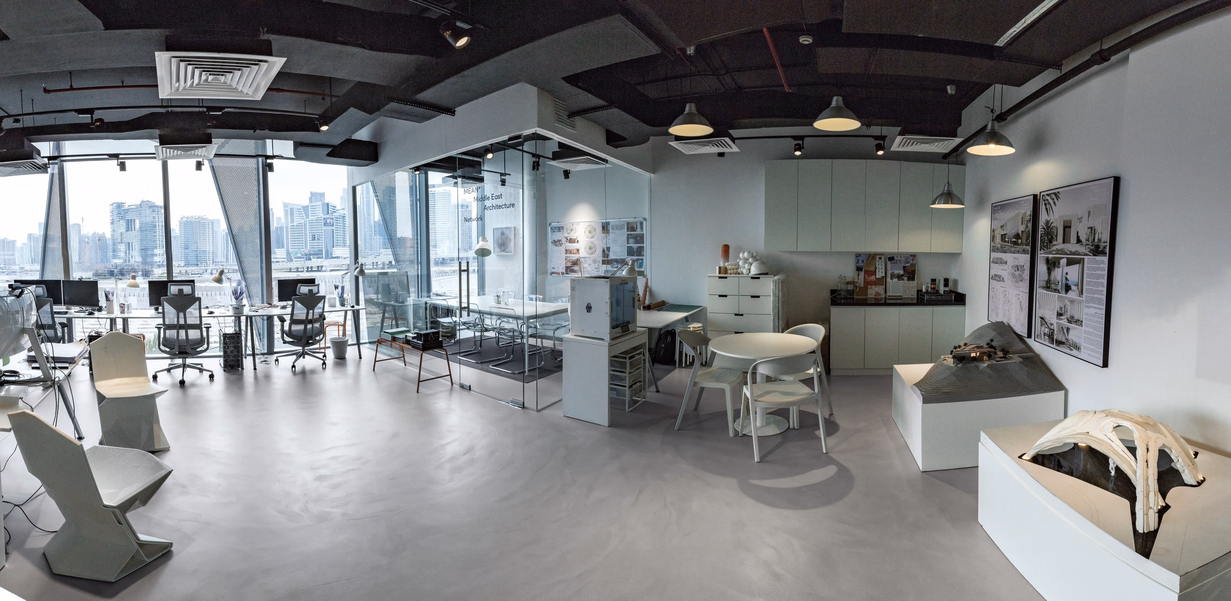 MEAN* studio in Dubai: open workspace with prototypes on plinths and a view of the city