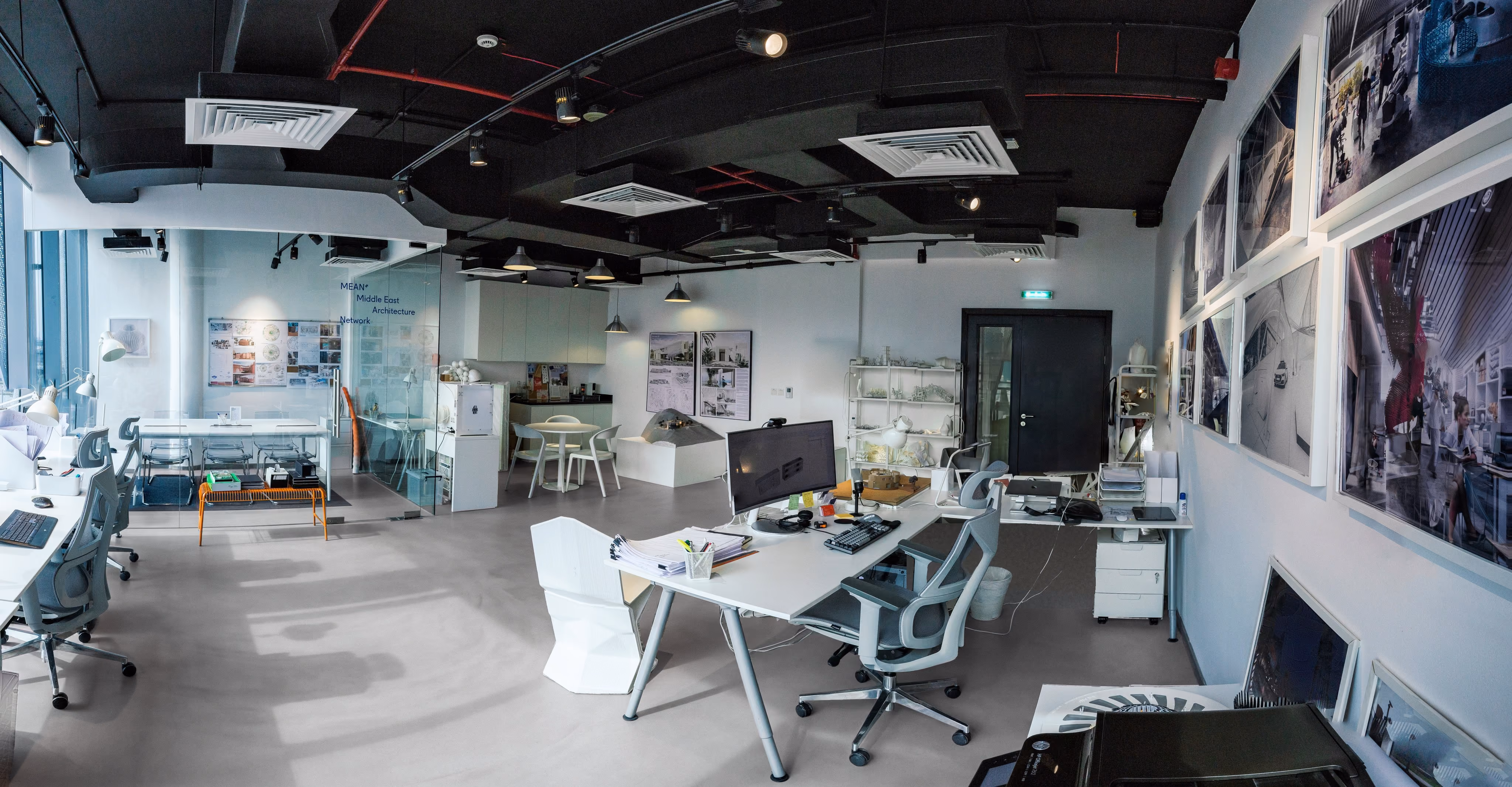 Desks, the glass meeting room and framed project images at the MEAN* studio