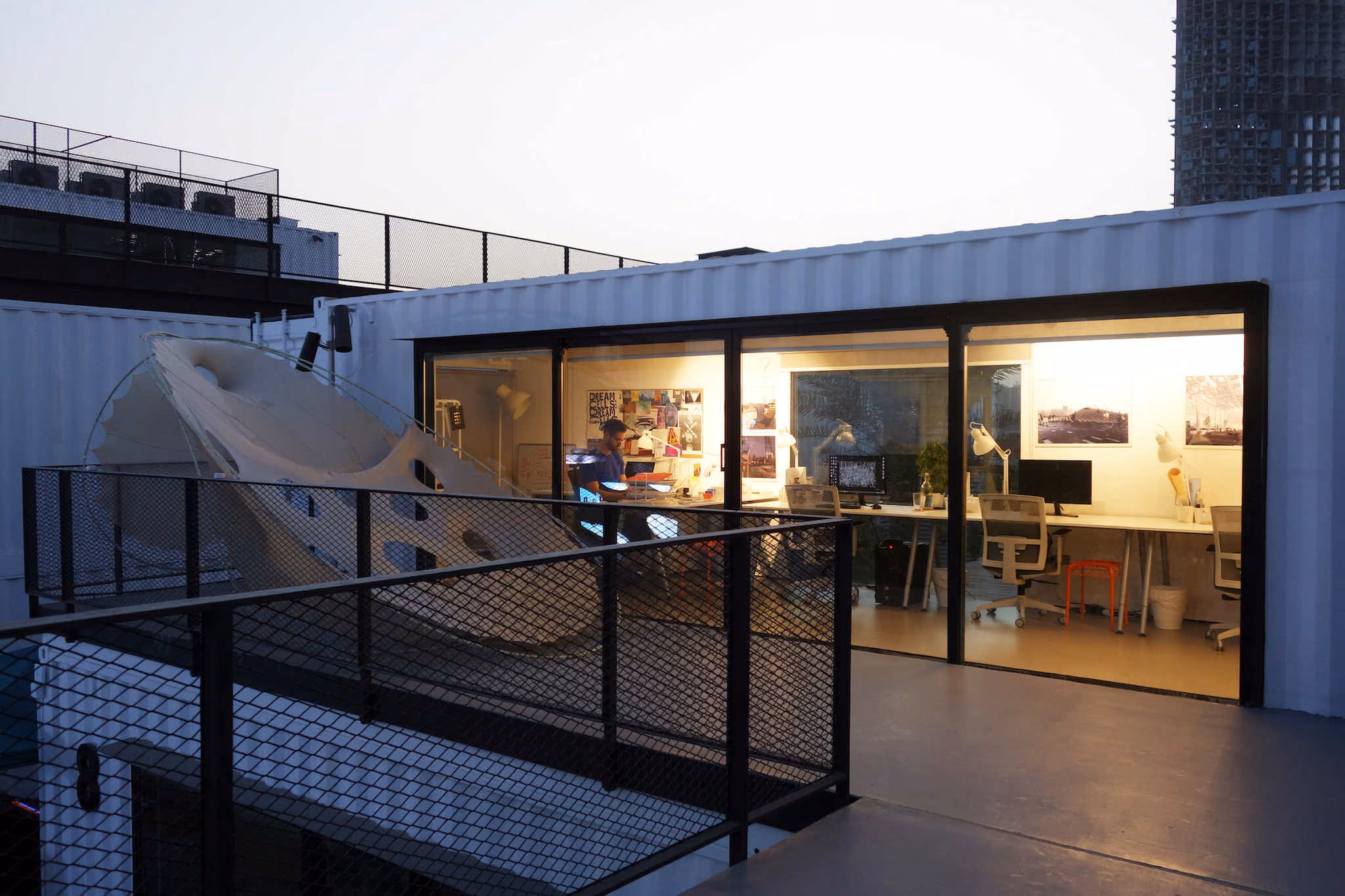 MEAN* studio at dusk, seen from the terrace through its glazed front