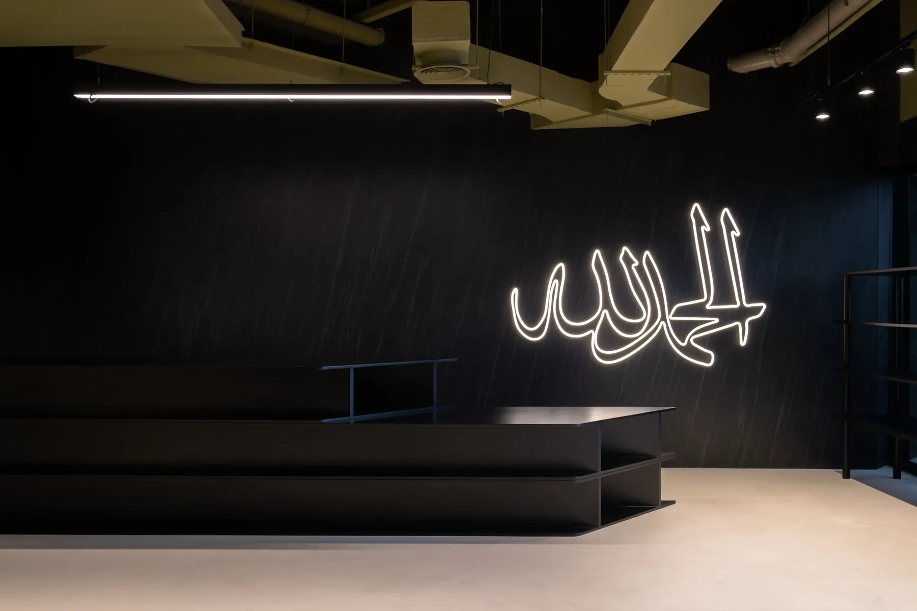 Send Location, Dubai: a black counter under a lit calligraphy sign.