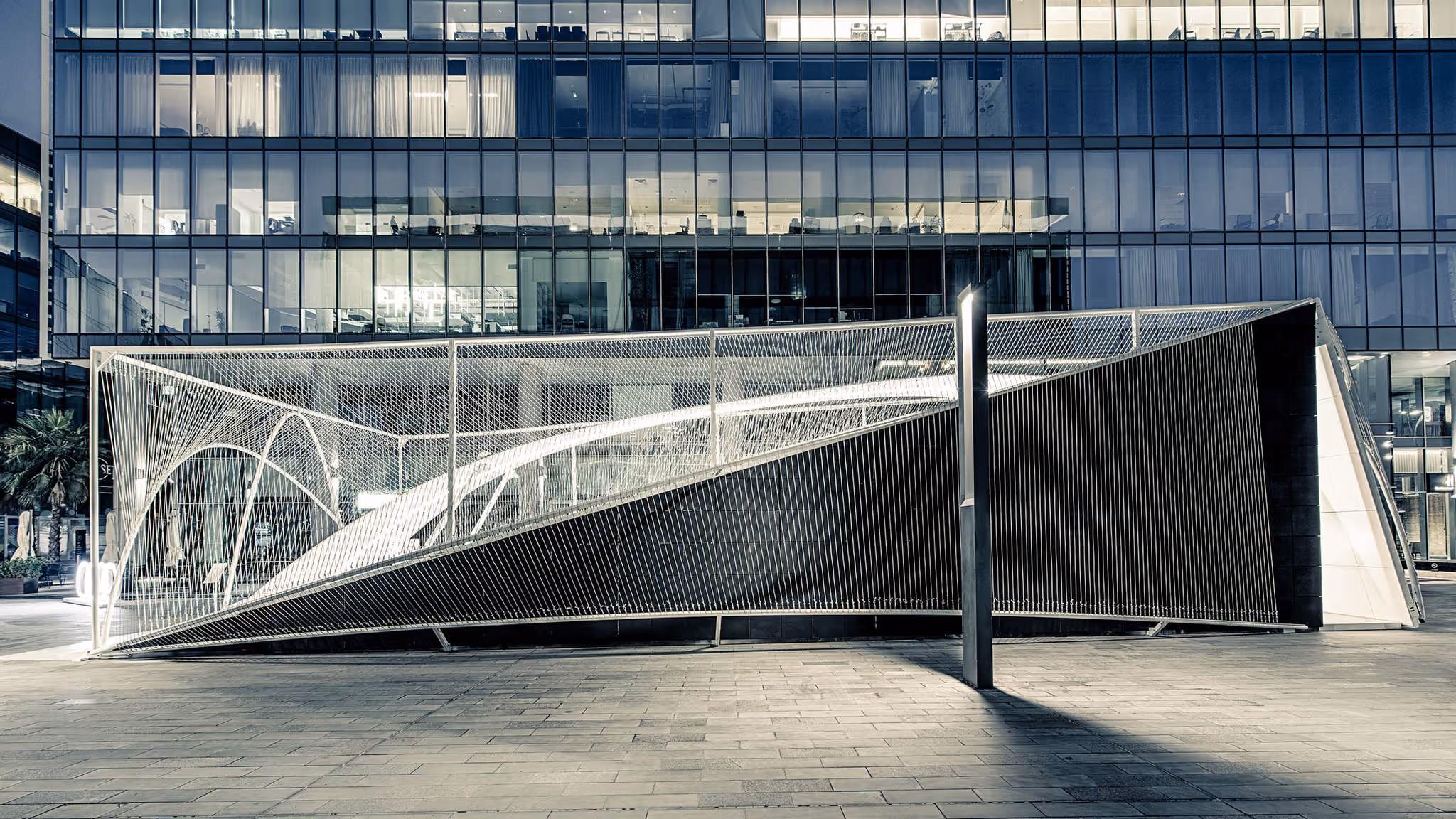 Curved woven structure of the Audi Innovation Hub illuminated at Dubai Design Week.