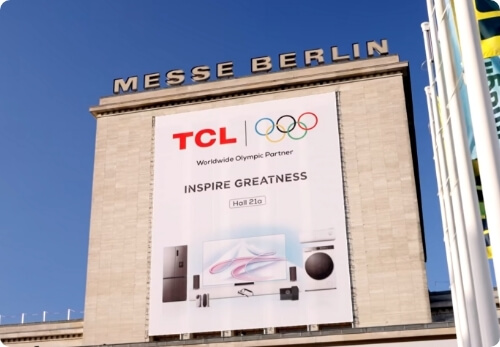 Large TCL Olympic Partner banner on Messe Berlin building under clear blue sky.