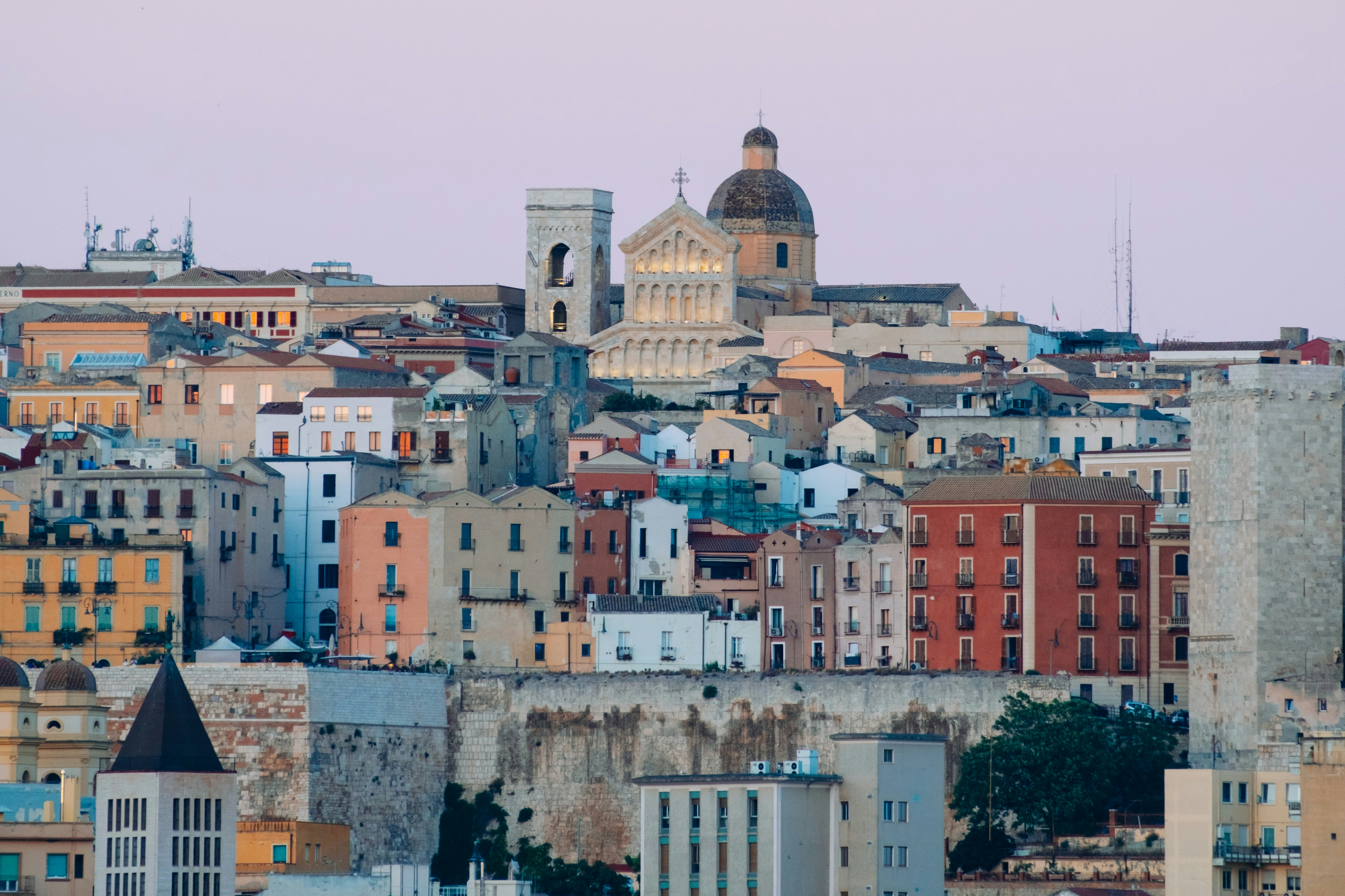 Panoramic view of a historic town with densely packed colorful buildings and a prominent cathedral with a dome and bell tower.