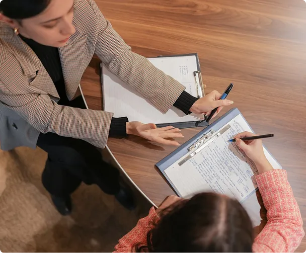Deux femmes discutant de la formation Analytics Engineer d'Ada Study, l'une prenant des notes sur un clipboard.