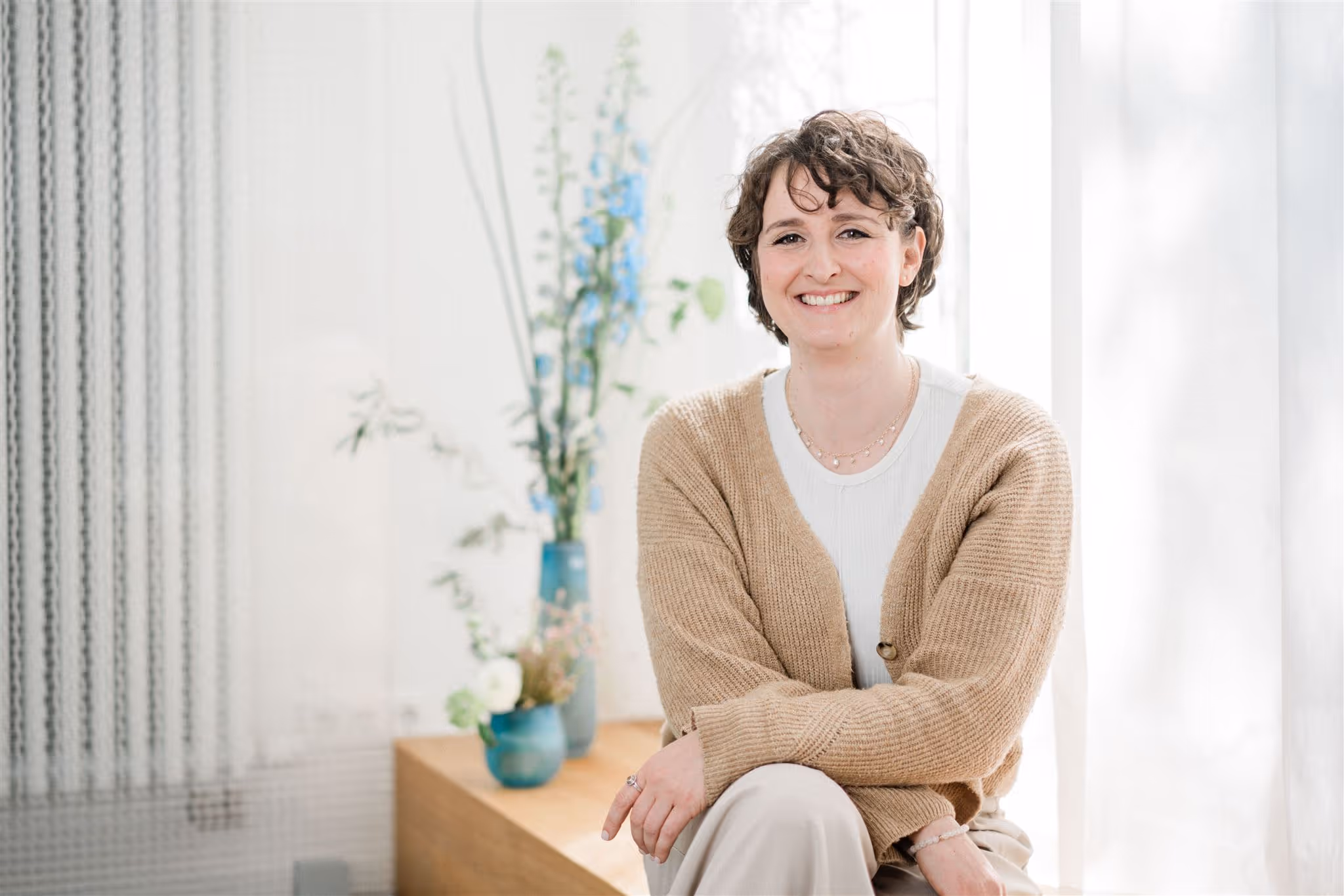 Julia Bobe, die vor einem hellen Hintergrund auf einem Holzbrett sitzt.